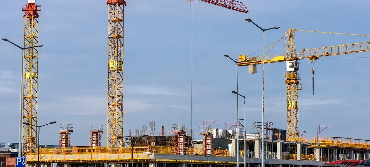 Constructing Your Influence: Building External Authority Multiple large yellow construction cranes with extended booms against a cloudy sky, symbolizing building and establishing a strong foundation.