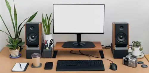 Staying Agile: Monitoring and Adapting Your Strategy A clean, organized desktop workspace with a computer monitor, keyboard, mouse, a green plant, and a notebook, symbolizing monitoring and analysis.